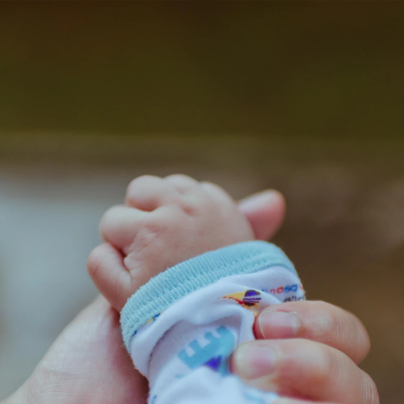 Eine Frauenhand hält eine sehr kleine Hand von einem Baby.